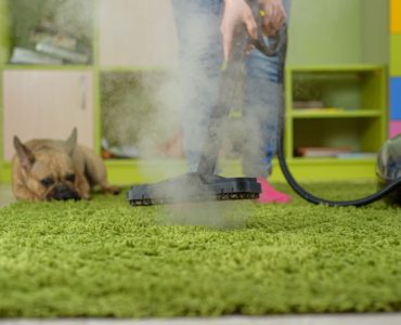 Une femme nettoie le tapis avec un nettoyeur vapeur dans la chambre des enfants