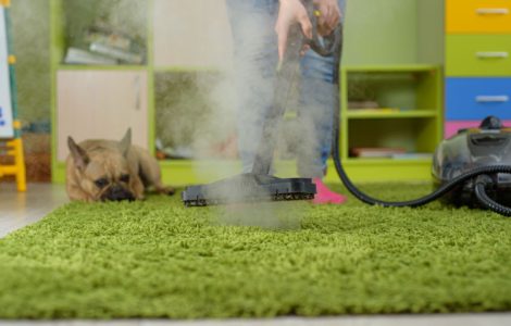 Une femme nettoie le tapis avec un nettoyeur vapeur dans la chambre des enfants