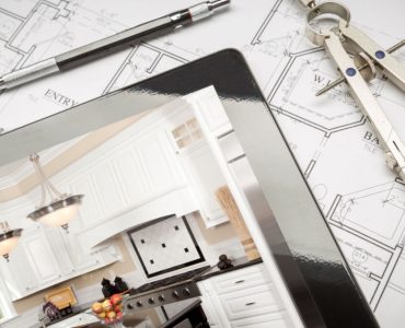 Une tablette, posée sur des plans de maison, montrant une illustration de cuisine