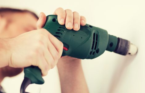 Un homme avec perceuse électrique fait un trou dans le mur