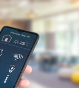 Zoom sur la main d’un homme tenant un smartphone pour contrôler l'équipement électrique de la maison