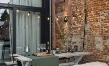 Une terrasse cosy, avec table et chaises en bois blanc, couverture en fourrure blanche…