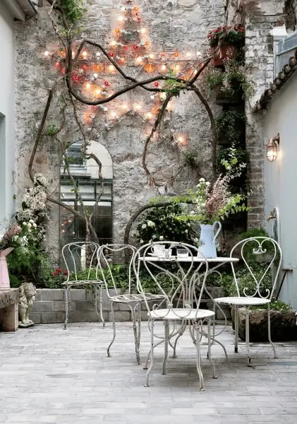 Un mobilier de jardin en fer forgé usagé sur une terrasse savamment décorée