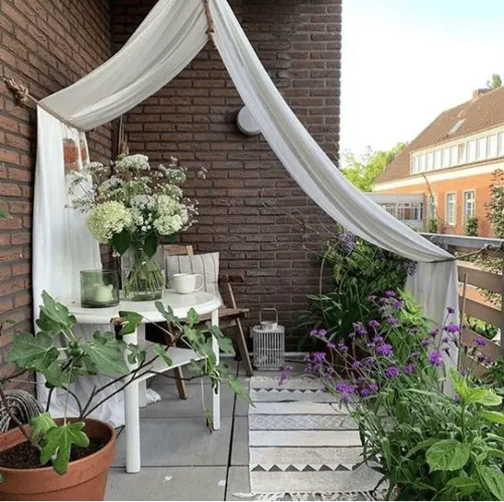 Un long voilage blanc sur la terrasse d'un balcon