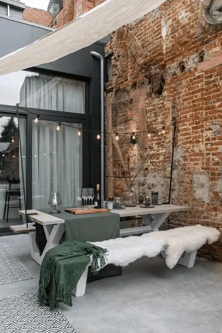 Une terrasse cosy, avec table et chaises en bois blanc, couverture en fourrure blanche…
