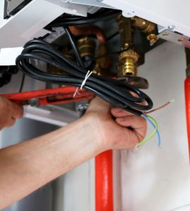 Zoom sur les mains d’un homme en train de fixer les raccords d’une chaudière
