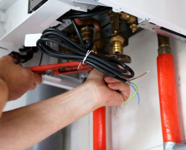 Zoom sur les mains d’un homme en train de fixer les raccords d’une chaudière