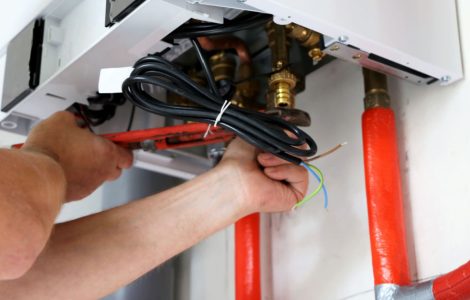 Zoom sur les mains d’un homme en train de fixer les raccords d’une chaudière