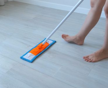 Une femme nettoie le sol en linoléum en utilisant une serpillière
