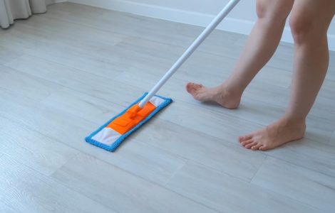 Une femme nettoie le sol en linoléum en utilisant une serpillière