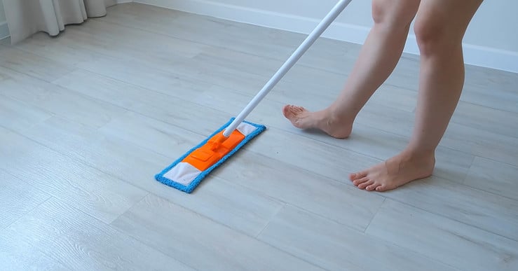 Une femme nettoie le sol en linoléum en utilisant une serpillière