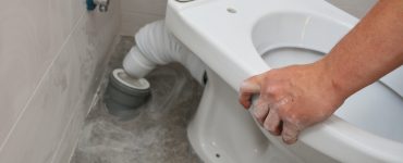 Zoom sur un homme reliant la cuvette de toilette au tuyau d'évacuation