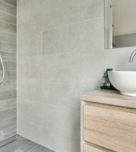 Une salle de bain ouverte avec un petit meuble lavabo en bois