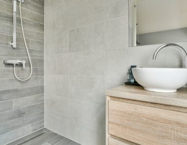 Une salle de bain ouverte avec un petit meuble lavabo en bois