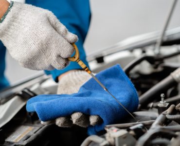 Un mécanicien en train de vérifier le niveau d’huile d’une voiture