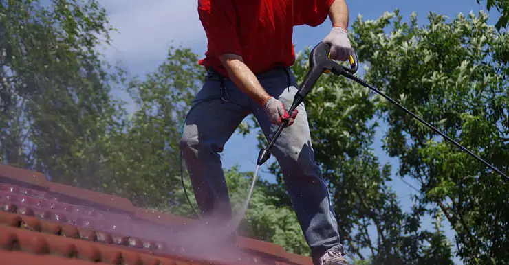 Un homme effectuant le lavage à haute pression d’une toiture en tuile