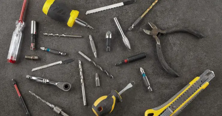 Différents outils posés sur une table : pince, tournevis, cutter...