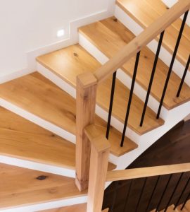 Un escalier en bois intérieur illuminé par des spots encastrés