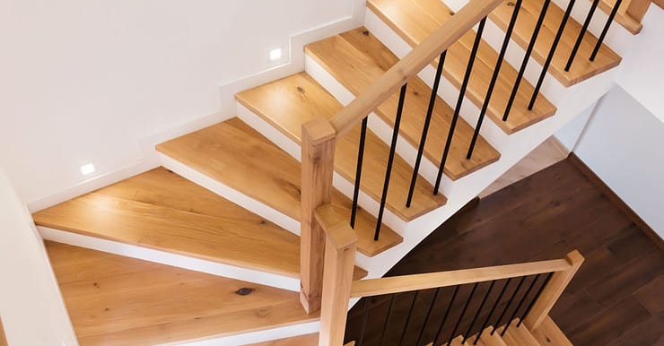 Un escalier en bois intérieur illuminé par des spots encastrés