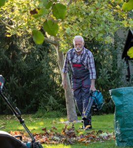 Un homme et une femme dans un jardin avec un souffleur de feuilles et une tondeuse