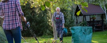 Un homme et une femme dans un jardin avec un souffleur de feuilles et une tondeuse