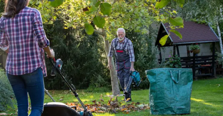 Un homme et une femme dans un jardin avec un souffleur de feuilles et une tondeuse