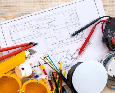 Différents outils de réparation électrique et un plan posés sur la table