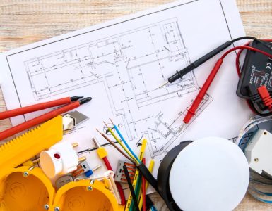 Différents outils de réparation électrique et un plan posés sur la table