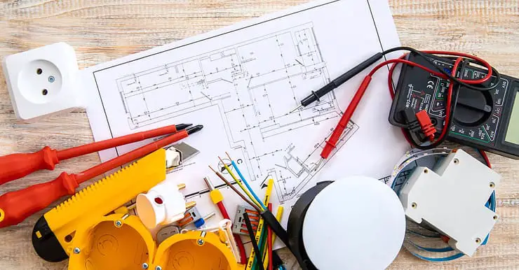 Différents outils de réparation électrique et un plan posés sur la table