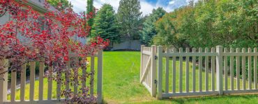 Une clôture de jardin en bois avec le portillon ouvert donnant sur la pelouse