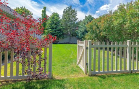Une clôture de jardin en bois avec le portillon ouvert donnant sur la pelouse
