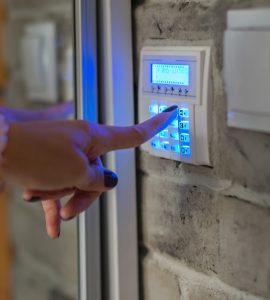 Une femme entrant le mot de passe sur le clavier de l'alarme d'une maison