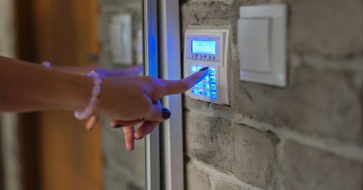 Une femme entrant le mot de passe sur le clavier de l'alarme d'une maison