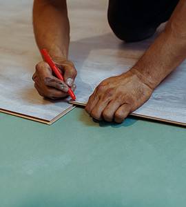 Un homme installant du stratifié de bois comme revêtement de sol