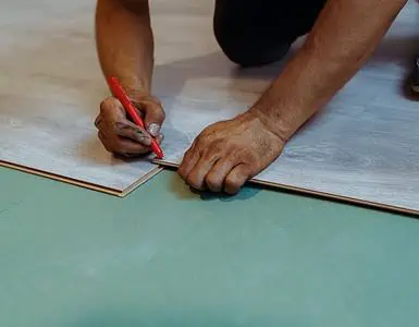 Un homme installant du stratifié de bois comme revêtement de sol