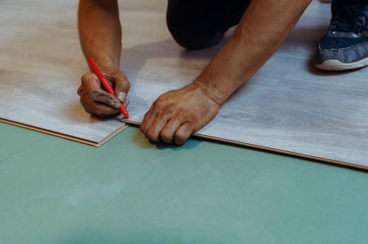 Un homme installant du stratifié de bois comme revêtement de sol