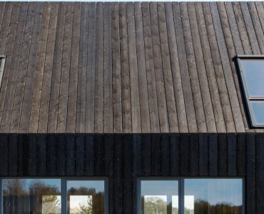 Façade d'une maison en planches de bois brûlées et des baies vitrées