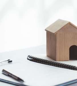 Maquette d’une petite maison en bois posée sur des documents sur la table