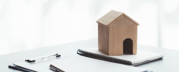 Maquette d’une petite maison en bois posée sur des documents sur la table