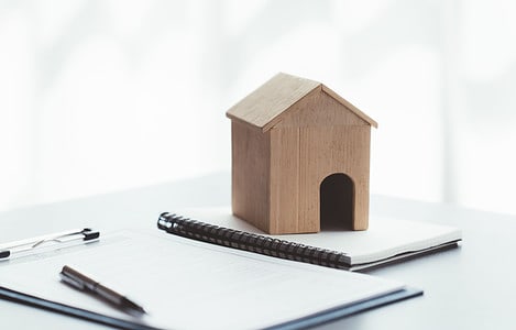 Maquette d’une petite maison en bois posée sur des documents sur la table