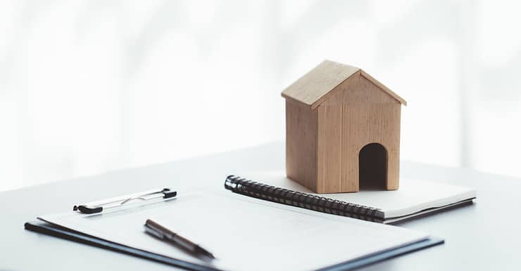 Maquette d’une petite maison en bois posée sur des documents sur la table