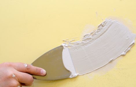 Zoom sur la main d’un homme appliquant un enduit mural à l’aide d’une spatule