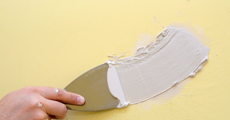 Zoom sur la main d’un homme appliquant un enduit mural à l’aide d’une spatule