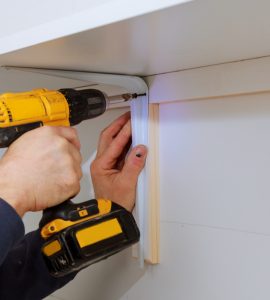 Homme installant des étagères en bois sur des murs à l'aide de crochets