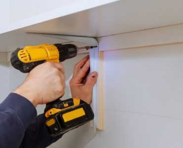 Homme installant des étagères en bois sur des murs à l'aide de crochets