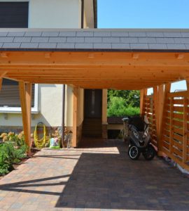 Un scooter garé sous un carport en bois devant une maison