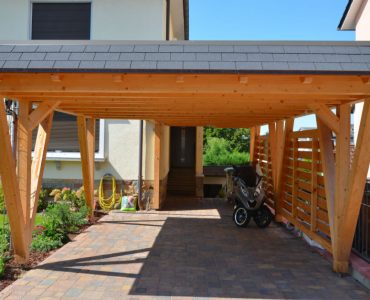 Un scooter garé sous un carport en bois devant une maison