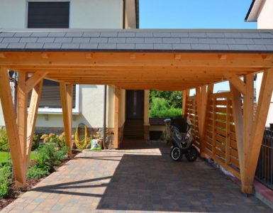 Un scooter garé sous un carport en bois devant une maison