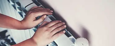 Un enfant se chauffe les mains sur le radiateur de la maison