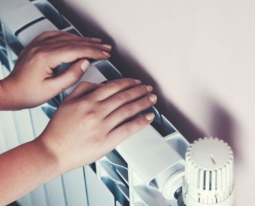 Un enfant se chauffe les mains sur le radiateur de la maison
